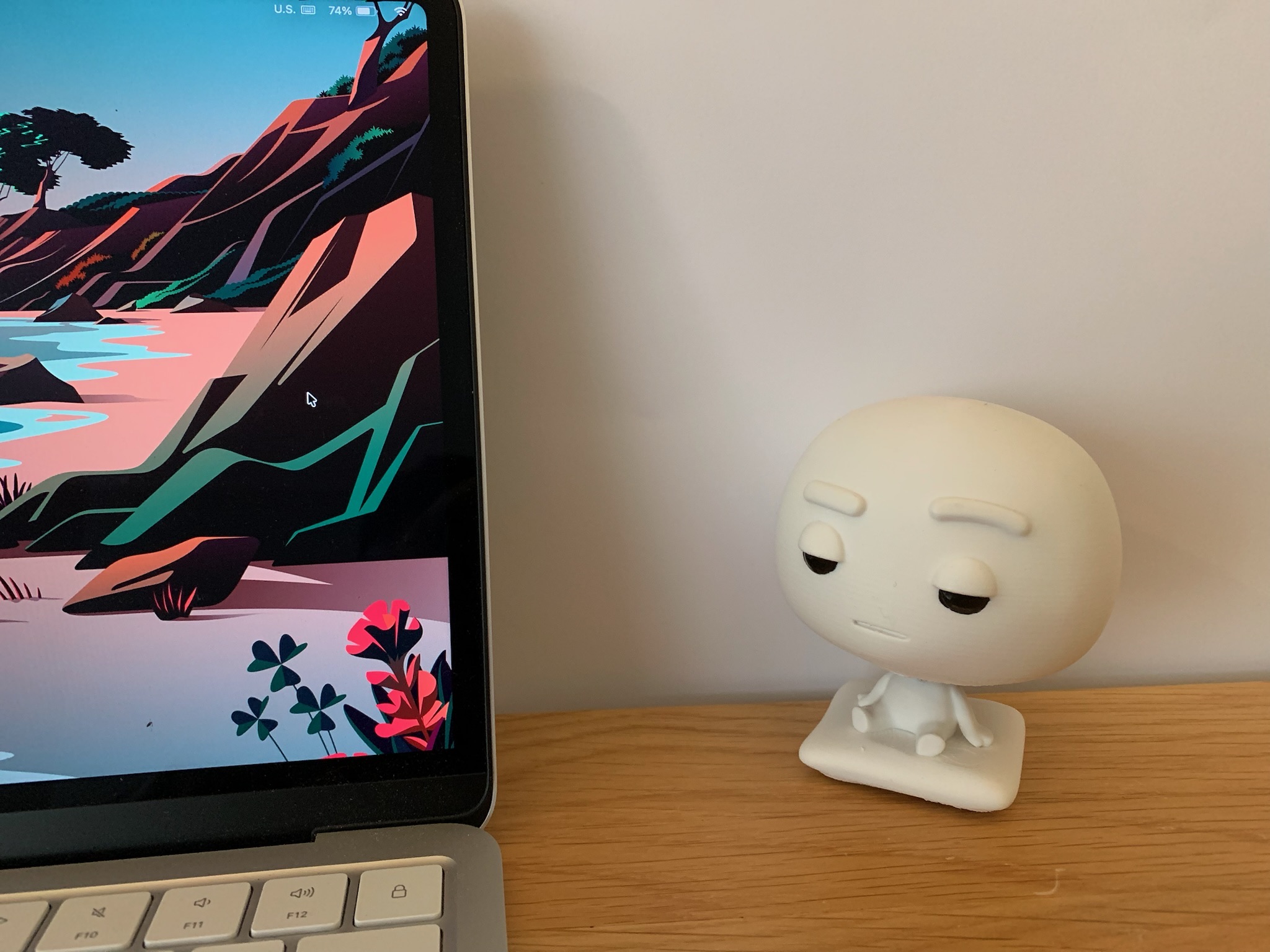 Pixl Nub sitting beside a MacBook on a wooden desk