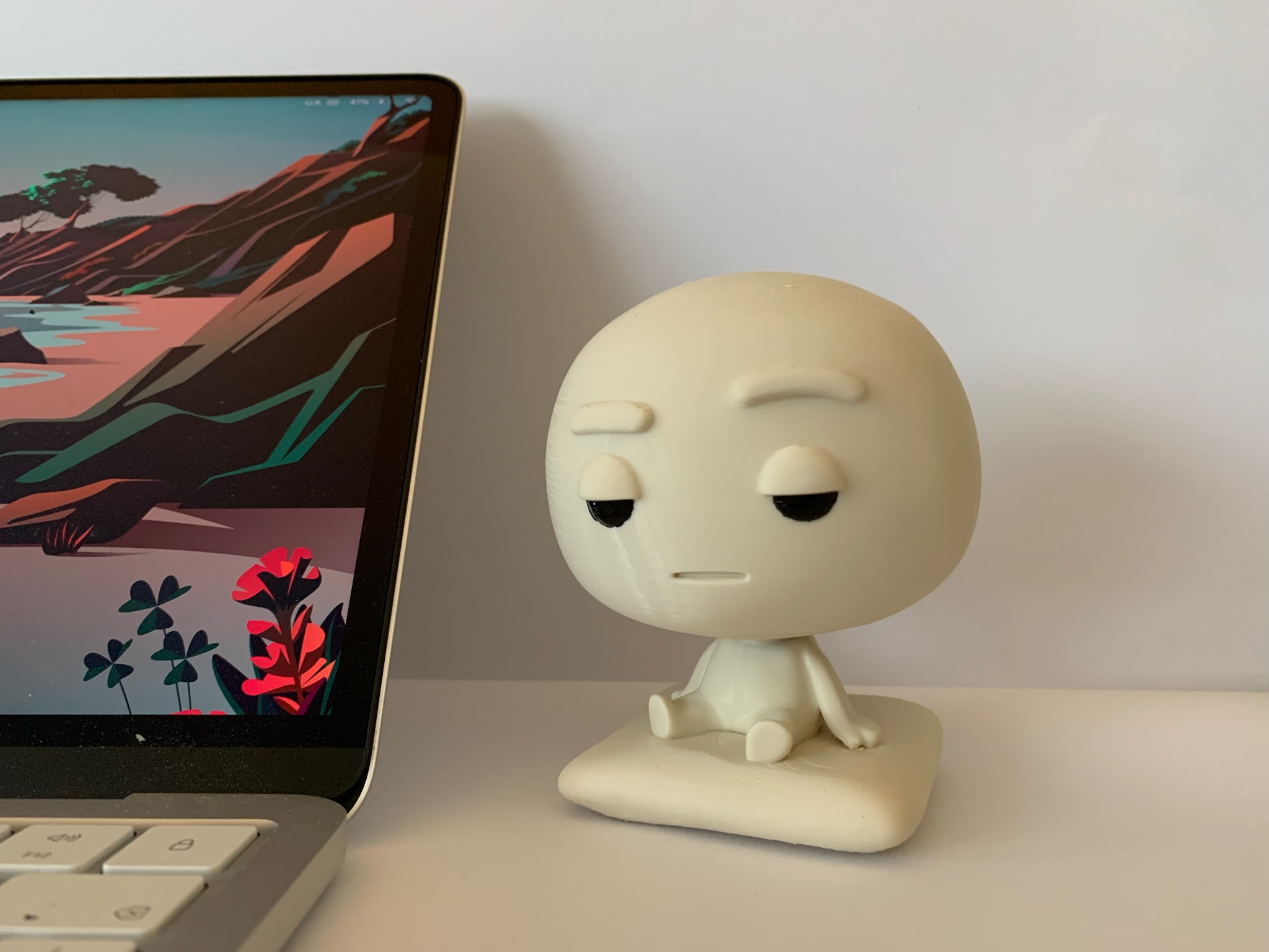 Pixl Nub sitting on a clean white desk beside a laptop with a colourful wallpaper