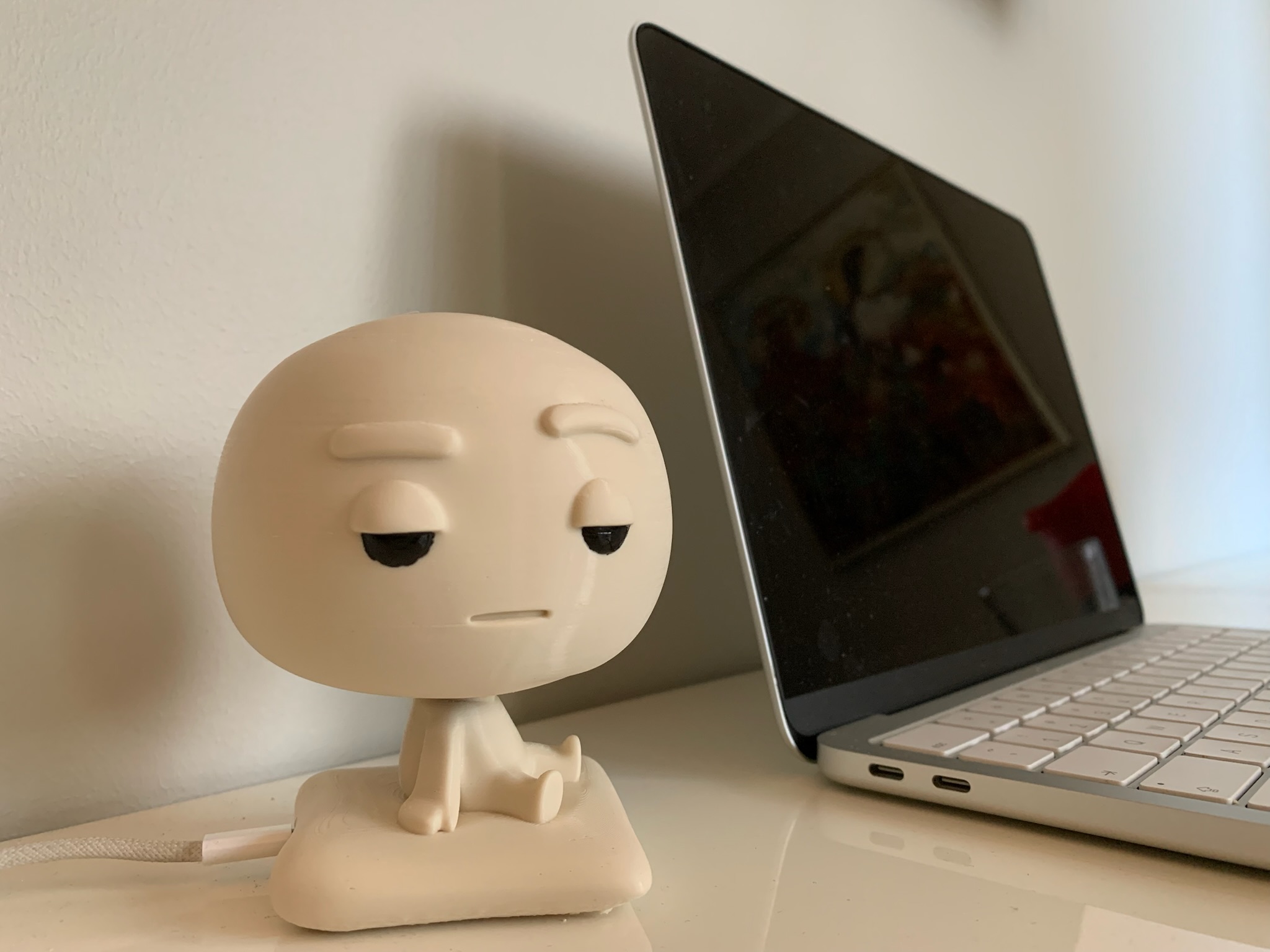 Pixl Nub on a clean white desk in front of a closed laptop